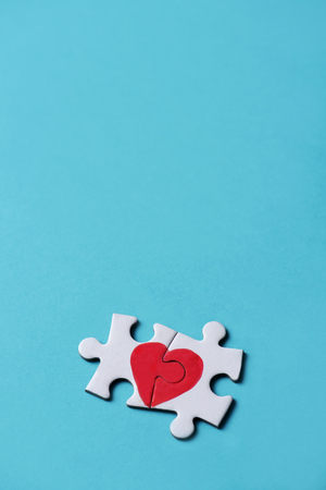 two pieces of a puzzle forming a heart, depicting the idea that love is a matter of two, on a blue background, with some blank space on topの写真素材
