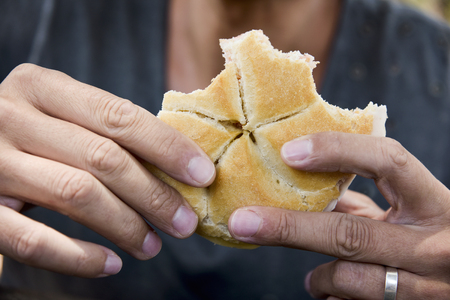 closeup of a caucasian man eating a sandwich, made with a vienna roll, outdoorsの写真素材