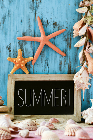 closeup of a chalkboard with the text summer written in it next to many conches, seashells and starfishes, against a blue rustic wooden backgroundの写真素材