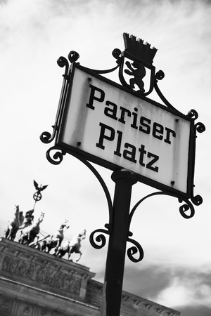 closeup of a nameplate in the street with the name ot the Pariser Platz in Berlin, Germany, with the Brandenburg Gate in the background, in black and whiteの写真素材