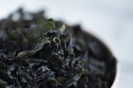 closeup of a pile of dried leaves of wakame, an Asian edible seaweed used in traditional soups such as the miso soup, on a white ceramic bowlの写真素材