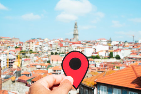 closeup of the hand of a young caucasian man with a red marker pointing the old town of Porto, in Portugal, highlighting the Torre dos Clerigos, the belfry of the Clerigos Church, in the backgroundの写真素材
