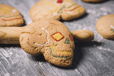 closeup of some homemade skull-shaped cookies for Hallowen, on a gray rustic wooden tableの写真素材