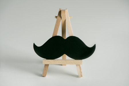 A black mustache on a wooden easel, on an on off-whiteの写真素材
