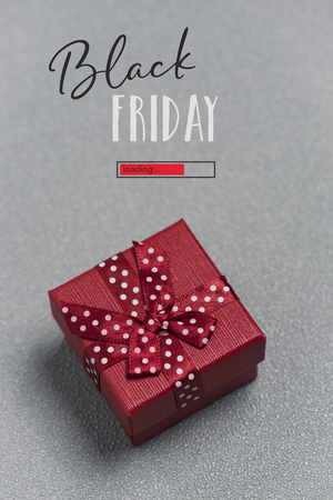 The text black friday, a red progress bar with the text loading, and a red gift box tied with a red ribbon and on a grayの写真素材