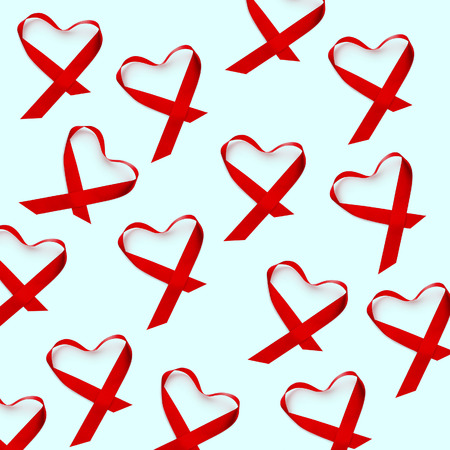 Some red ribbons, for the fight against AIDS, placed as hearts, on a pale green or pale blueの写真素材