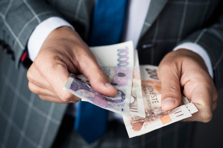 closeup of a young caucasian businessman, wearing an elegant gray suit, counting some czech koruna...