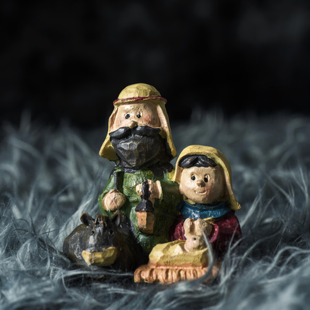 the holy family, the child jesus, the virgin mary and saint joseph, on a gray artificial fur, against a dark backgroundの写真素材