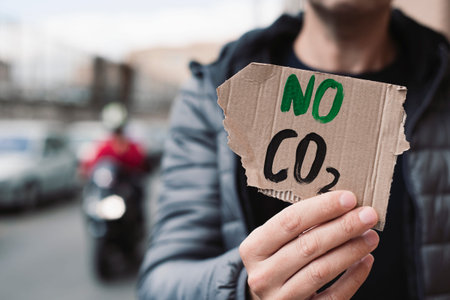 closeup of a young caucasian man, on the street, showing a brown cardboard signboard with the text...