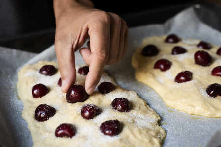 closeup of a young caucasian man prepaing some coca de cireres, a cherry sweet flat cake typical of Catalonia, Spainの写真素材