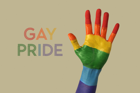 closeup of the palm of the hand of a person, painted as the rainbow flag, and the text gay pride written with the colors of the rainbow flag, against an off-white backgroundの写真素材