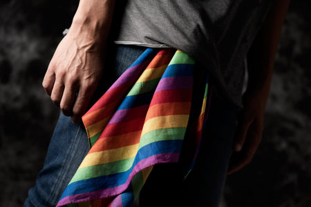 closeup of a young caucasian man with a rainbow-patterned handkerchief hanging from his jeans,...