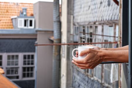 closeup of a young caucasian man having a coffee in the balcony of his home, hotel or vacation rental in the old town of a European cityの写真素材