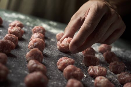 closeup of a caucasian man preparing some meatballs with raw minced meat on a dark gray wooden table or countertopの写真素材