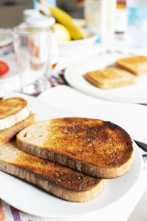 closeup of some toasts in a white ceramic plate on a table set for breakfast or dinnerの写真素材