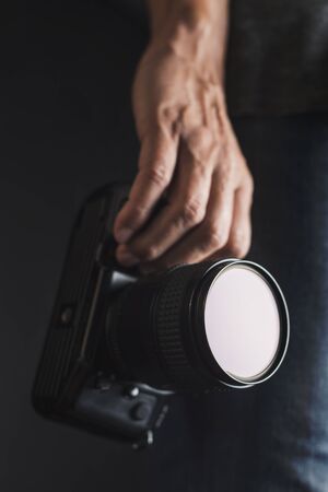 closeup of a young caucasian man with a reflex camera in his handの写真素材