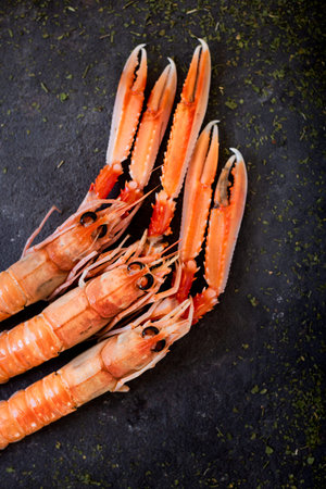 high angle view of some fresh raw Norway lobsters, also known as scampi, on a black slate surface...