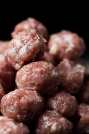 closeup of a pile of raw homemade meatballs ready to be cooked against a black backgroundの写真素材