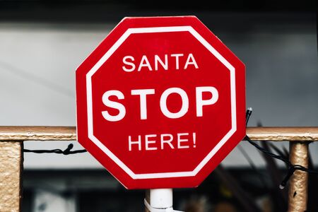 closeup of a signboard with the text santa stop here in the railings of a balconyの写真素材