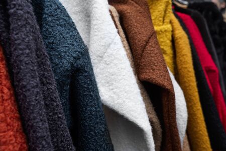 closeup of some sweaters of different colors hanging on a rackの写真素材
