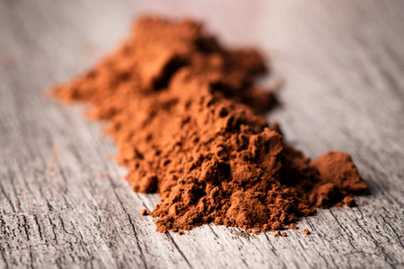 Closeup of a pile of cocoa powder on a gray rustic wooden table