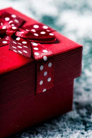 closeup of a red gift box, tied with a nice red ribbon, on the snow
