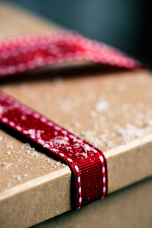 Closeup of a brown gift box, tied with a nice red ribbon, on the snow