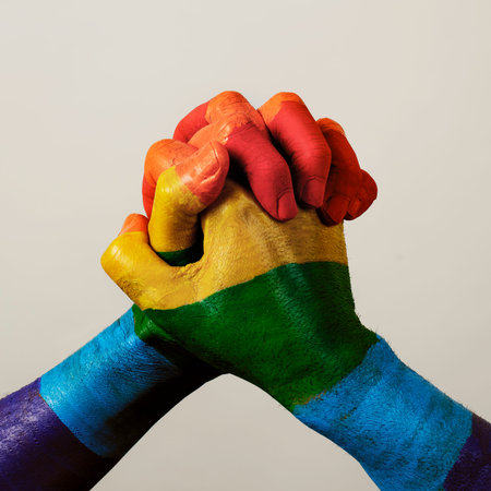 Two men clasping their hands together, painted as the rainbow flag, against an off-white
