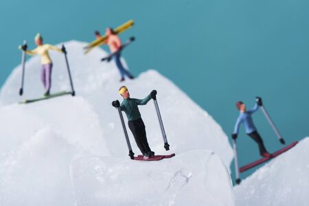 a group of miniature skiers on an ice landscape against a blue backgroundの写真素材