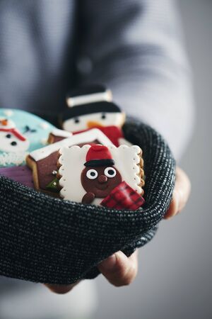 Closeup of a young caucasian man with a pile of christmas cookies with different shapes and colors in his handsの写真素材