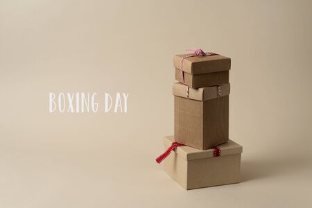 a pile of brown gift boxes tied with different strings and ribbons, and the text boxing day on a brown backgroundの写真素材