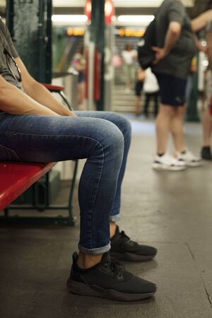 closeup of a young caucasian man, wearing casual clothes, sitting in a wooden bench in an underground stationの写真素材
