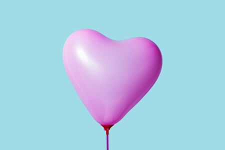 a pink heart-shaped balloon against a blue backgroundの写真素材