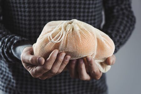 Closeup of a man holding a textile reusable mesh bagの写真素材