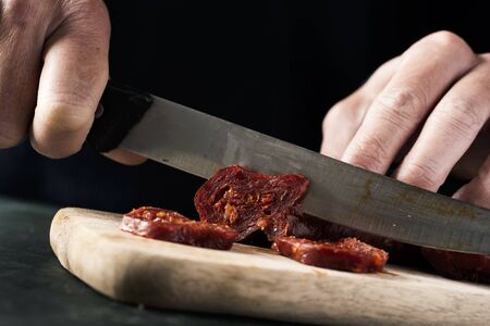 Closeup of a man cutting some slices of chorizo, a cured pork sausageの写真素材