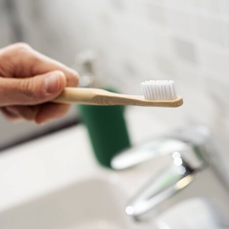 Closeup of a caucasian man using a bamboo toothbrush in the bathroomの写真素材