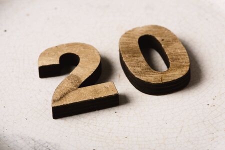 Closeup of two wooden three-dimensional numbers forming the number 20 on a cracked white ceramic surfaceの写真素材
