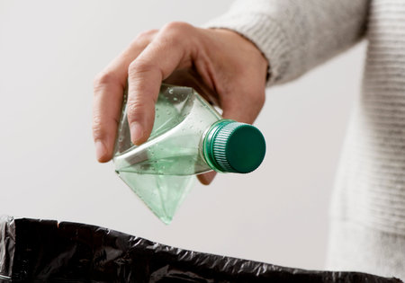 closeup of a young caucasian man about to throw an empty plastic bottle to the trash bin