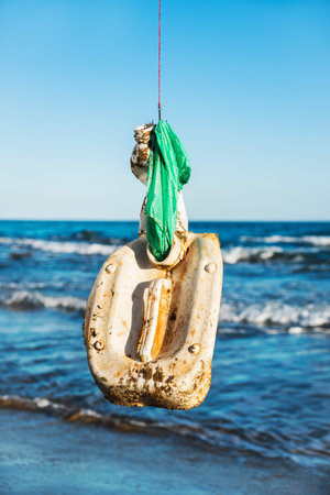 closeup of some used plastic objects in a fish hook, freshly fished in the ocean, in front of the...