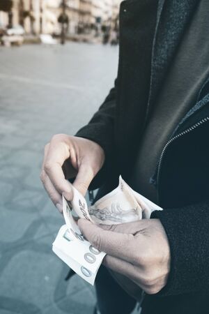 Close up of a young caucasian man on the street counting some banknotesの写真素材