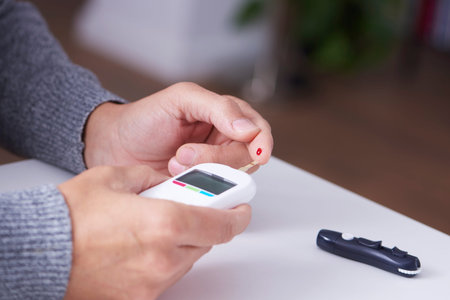 Close up of a caucasian man measuring his blood glucose level with a glucose meter