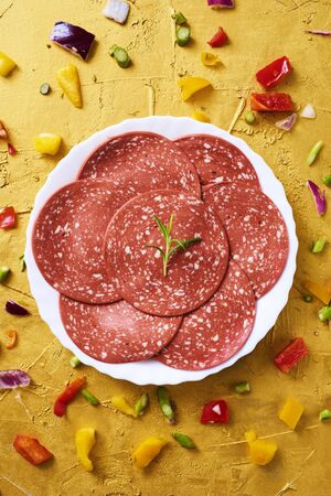 Some slices of veggie salami in a plate, on a golden textured surfaceの写真素材