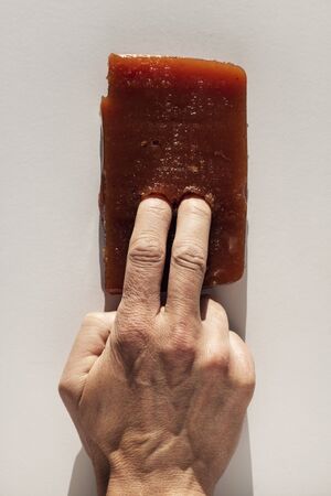 View of a caucasian man putting two fingers in a piece of homemade quince cheese on whiteの写真素材