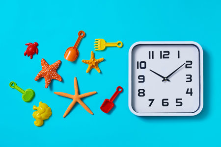high angle view of a clock, some starfishes and some different beach toys, such as toy shovels and...