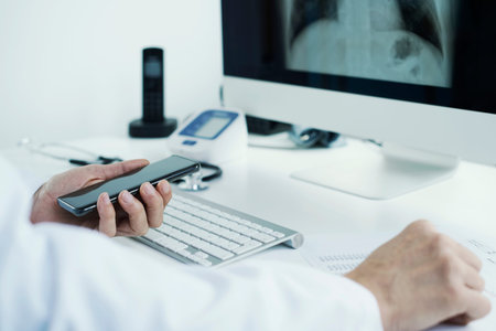 closeup of a young doctor man, wearing a white coat, sitting at his desk checking a chest radiograph...