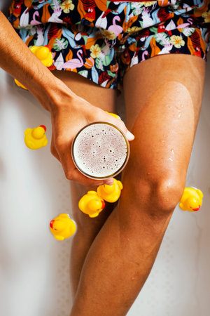 high angle view of a young caucasian man, wearing swimsuit, having a glass of refreshing beer in his...