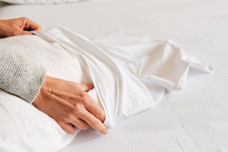 closeup of a young caucasian man introducing a pillow into a white pillow case as he is making the...