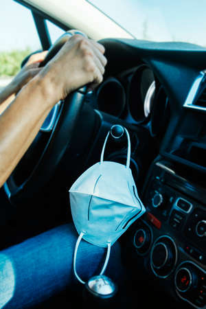 closeup of a man driving a car while his face mask is hanging from a lever next to the steering wheelの写真素材