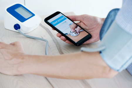 closeup of a young caucasian man, measuring his own blood pressure with a sphygmomanometer, having...