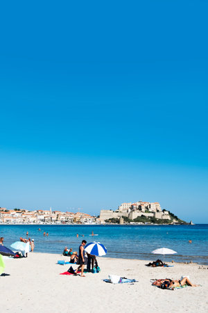 CALVI, FRANCE - SEPTEMBER 21, 2018: People enjoying the beach in Calvi, Corsica, France, with its famous citadel on the top of a promontory on the right in the backgrondのeditorial素材